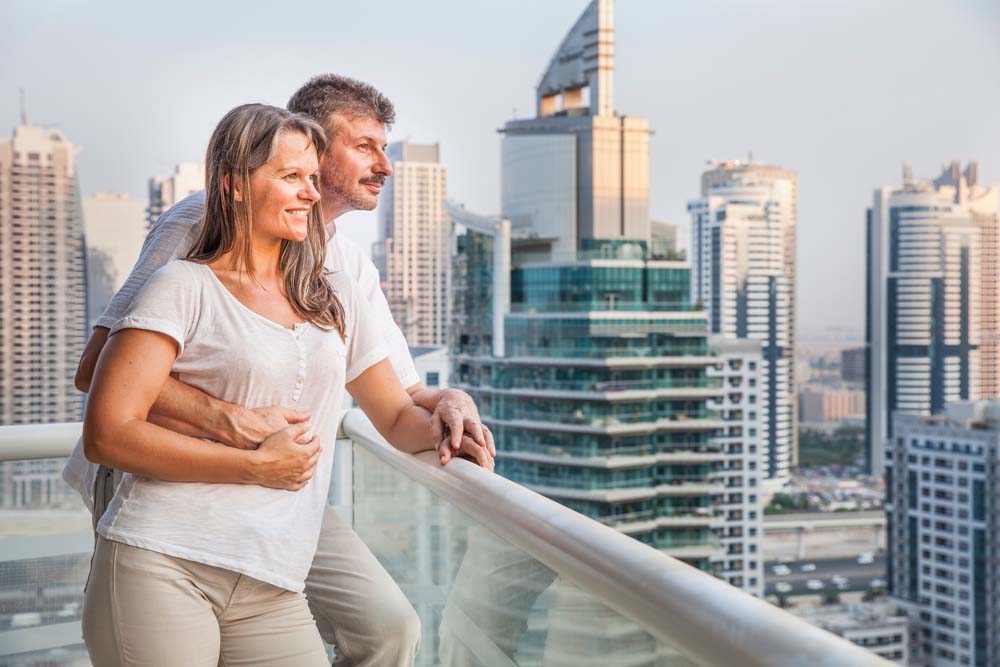 A couple looking out over a city skyline from a high balcony